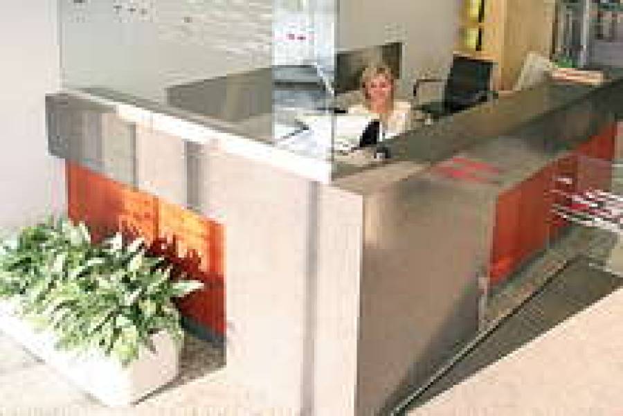 Стойка в приемной административного здания LMT изготовлена из вишневого дерева и кориана. Этот материал, изобретенный в 1967 году, способен имитировать почти любые поверхности. Из него отливаются стойки ресепшн всех форм, цветов и размеров.
